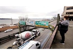 In this photo taken Wednesday, Jan. 2, 2019, a woman takes a photo toward Elliott Bay as Alaskan Way Viaduct traffic rolls past her below ahead of an upcoming closure of the roadway, in Seattle. The double-decker highway along Seattle's waterfront is set to shut down for good Friday, Jan. 11, ushering in what officials say will be one of the most painful traffic periods in the city's history. The 65-year-old viaduct is being replaced by a four-lane Highway 99 tunnel, scheduled to open several weeks after the viaduct's closure.