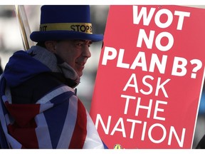 Anti Brexit protester Steve Bray who is almost permanently demonstrating outside the Houses of Parliament watches the traffic as he holds up placards in London, Monday, Jan. 28, 2019. British Prime Minister Theresa May faces another bruising week in Parliament as lawmakers plan to challenge her minority Conservative government for control of Brexit policy.
