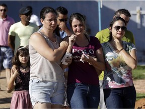 The widow of Vale SA employee Edgar Carvalho Santos, victim of the collapsed dam, center, is comforted by friends and relatives during his burial, in Brumadinho, Brazil, Tuesday, Jan. 29, 2019.  Officials said the death toll was expected to grow "exponentially," since no had been rescued alive since Saturday.