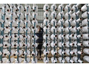 In this Jan. 21, 2019, photo, a worker adjusts a cotton string roll at a textile factory in Hangzhou in east China's Zhejiang province. An official measure of China's manufacturing improved in January but forecasters say economic activity is sluggish as Chinese leaders try to resolve a tariff battle with Washington. (Chinatopix via AP)