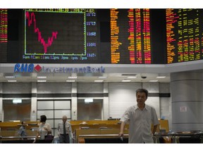 An Investor walks in front of stock trading boards at a private stock market gallery in Kuala Lumpur, Malaysia, Wednesday, Jan. 30, 2019. Asian markets rose Wednesday as traders awaited a Federal Reserve policy meeting and U.S.-China talks.