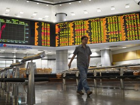 An investor walks in front of stock trading boards at a private stock market gallery at private stock exchange gallery in Kuala Lumpur, Malaysia, Friday, Jan. 25, 2019. Asian shares were mostly higher Friday after a moderate rise on Wall Street.