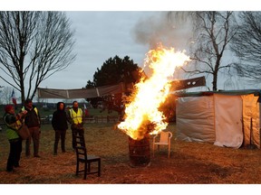 Protestors wearing yellow vests stand next to a fire in a makeshift camp on a roundabout near Senlis, north of Paris, Thursday, Jan. 10, 2019. With its makeshift grocery, camp beds and community spirit, the large central island about 60 kilometers north of Paris has been transformed over the past two months into an encampment where dozens of yellow vests protesters gather day in day out to organize their long-standing fight against the French government.