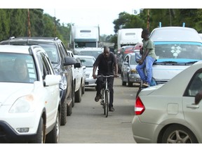 A cyclist makes his way through a fuel queue in the capital Harare, Friday, Jan. 11, 2019. Zimbabwe's president has more than doubled the price of gasoline, hoping the increase will end severe shortages that are fueling public anger.