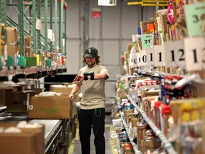 An example of an online grocer's distribution centre, where a worker checks his list to ensure the box contains the items ordered.