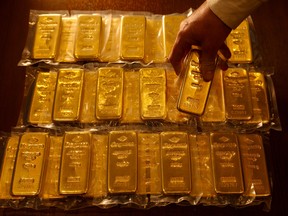 An employee of the Sharps Pixley showroom in London holds one of 32 one-kilogram bars of gold.