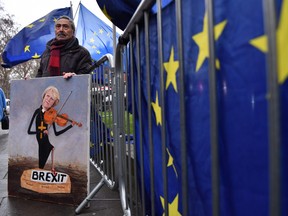 Political satire artist Kaya Mar poses with one of his artworks depicting Britain's Prime Minister Theresa May outside the Houses of Parliament in central London on January 16, 2019.