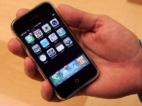 A customer holds the first Apple iPhone on June 29, 2007, which at that time cost $499 to $599.