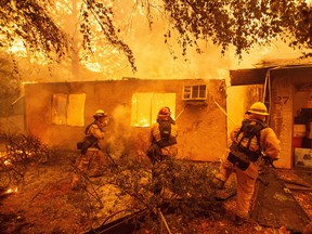 Firefighters push down a wall while battling against a burning apartment complex in Paradise, north of Sacramento, California.