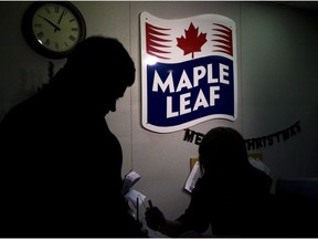 A Maple Leaf Foods employee, right, signs in a person from the media at the company's meat facility in Toronto on Monday, December, 15, 2008. Maple Leaf Foods Inc. raised its dividend as it reported its fourth-quarter profit fell compared with a year ago.