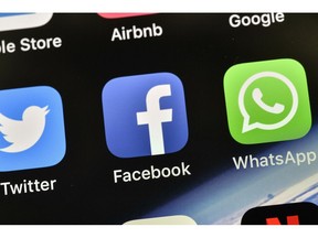 FILE - In this Thursday, Nov. 15, 2018 file photo the icons of Facebook and WhatsApp are pictured on an iPhone in Gelsenkirchen, Germany. German antitrust authorities have issued a ruling prohibiting Facebook from combining user data from different sources.