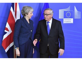 In this Thursday, Feb. 7, 2019 photo European Commission President Jean-Claude Juncker, right, prepares to shake hands with British Prime Minister Theresa May, left, before their meeting at the European Commission headquarters in Brussels, Belgium. EU Commission President Jean-Claude Juncker says he can't rule out that a delayed Brexit could mean the United Kingdom would participate in this spring's European Parliament election.