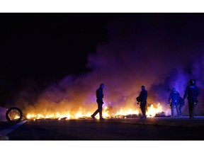 Police officers try to remove burning tires, set by demonstrators to block a highway in protest of the imprisonment of pro-independence political leaders during a general strike in Catalonia, Spain, Thursday, Feb. 21, 2019.