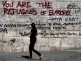 A woman walks past graffiti outside the Athens' Academy in 2012. For almost a decade the people of Greece have lived with unemployment, insecurity and debt.