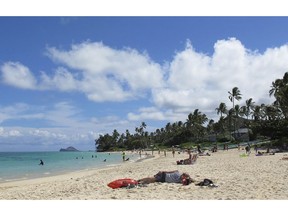 FILE - This Oct. 29, 2013 file photo shows people at Lanikai Beach, a popular neighborhood for vacation rentals, in Kailua, Hawaii. Hawaii says a judge should compel Airbnb to hand over 10 years of receipts and other documents from its hosts because the home-sharing platform has acknowledged that hosts aren't fully complying with state tax laws. A hearing is scheduled for Thursday, Feb. 8, 2019.