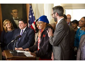 Ieshia Townsend, a McDonald's employee in Chicago, speaks about what a rise in the minimum wage will mean to her and her family during a ceremony where Gov. J.B. Pritzker, left, signed SB1 into law Tuesday, Feb. 19, 2019 at the Executive Mansion in Springfield, Ill. The law will gradually hike the state's minimum wage to $15 an hour by 2025.