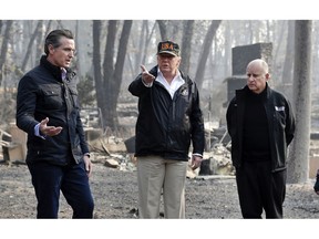 FILE - In this Nov. 17, 2018, file photo, President Donald Trump talks with then Gov.-elect Gavin Newsom, left, and as California Gov. Jerry Brown listens during a visit to a neighborhood impacted by the wildfires in Paradise, Calif. California Gov. Gavin Newsom says the Trump administration is engaging in "political retribution" by trying to take back $3.5 billion granted for the state's high-speed rail project. The Democratic governor says President Donald Trump is reacting to California suing over Trump's emergency declaration to pay for a wall along the U.S.-Mexico border.