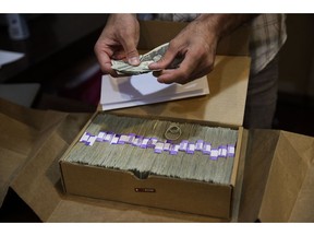 FILE - In this June 27, 2017 file photo, the proprietor of a medical marijuana dispensary prepares his monthly tax payment, over $40,000 in cash, at his Los Angeles store. Congress on Wednesday, Feb. 13, 2019, was urged to fully open the doors of the nation's banking system to the legal marijuana industry, a change that supporters say would reduce the risk of crime and resolve a litany of problems for pot companies from paying taxes to getting a loan.