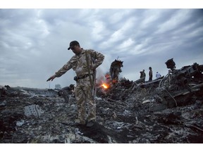 FILE - In this July 17, 2014 file photo, people walk amongst the debris at the crash site of a passenger plane near the village of Grabovo, Ukraine. The Dutch foreign minister said Thursday Feb. 7, 2019, that the Netherlands is in diplomatic discussions with Russia about his country's assertion that Moscow bears legal responsibility for the downing of a Malaysian passenger jet over Ukraine in 2014.