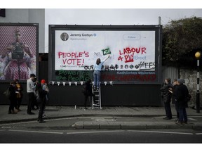 Young members of Britain's opposition Labour party write on a billboard why they want Jeremy Corbyn the party leader to back a "People's Vote" second referendum on Britain's European Union membership, during a publicity stunt in Islington North, Corbyn's north London constituency, Tuesday, Feb. 12, 2019. The event was organized Tuesday by "For our Future's Sake" (FFS), a nationwide group of students and young people working to stop Brexit, with the billboard provided by "Led By Donkeys" a remain supporting group using online crowd funding to pay for billboard space to put up posters highlighting quotes on Brexit made by politicians and organizations.