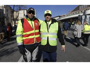 Unionist from the CGT (General Working Confederation) Mourad, left, and Yellow Vest protester Daniel pose together during a march in Marseille, southern France, Tuesday, Feb. 5, 2019. French public workers are striking in protest against French President Emmanuel Macron's policies and demonstrations are taking place across the country with the CGT labor union calling for a general strike.