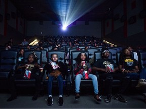 FILE - In this Feb. 19, 2018, file photo, Mari Copeny, third from left, watches a free screening of the film "Black Panther" with more than 150 children, after she raised $16,000 to provide free tickets in Flint Township, Mich. Streaming services are starting to catch up on getting the latest movies quickly, yet they are no match for the main attraction of movie theaters: no distractions from Facebook, online chats, household chores and what not.