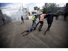 Demonstrators drag the body of a fellow protester toward police, as a form of protest after police shot into the crowd in which he died, during a demonstration demanding the resignation of Haitian President Jovenel Moise near the presidential palace in Port-au-Prince, Haiti, Tuesday, Feb. 12, 2019. Protesters are angry about skyrocketing inflation and the government's failure to prosecute embezzlement from a multi-billion Venezuelan program that sent discounted oil to Haiti.