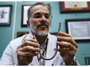 Trauma surgeon Joao Rezende-Neto poses for a photograph holding a working tracheotomy device at his office in St. Michael's Hospital in Toronto on Wednesday, Jan. 30, 2019. In Dr. Joao Rezende-Neto's 25-year career as a trauma surgeon, he's only twice dealt with patients who insisted on forking over big bucks to buy equipment for a procedure. One of the times was in Brazil, where medical technology is far less advanced, and his patient needed a tracheostomy, a procedure involving an incision made in the windpipe to clear breathing obstructions.
