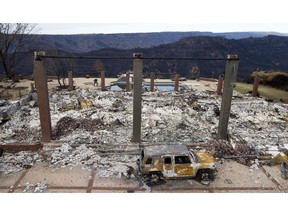 FILE - In this Dec. 3, 2018 file photo, a vehicle rests in front of a home leveled by the Camp Fire in Paradise, Calif. Pacific Gas & Electric says its equipment may have ignited the 2018 Camp Fire, which killed 86 people and destroyed an entire town in Northern California. The embattled utility said Thursday, Feb. 28, 2019,  it's taking a $10.5 billion charge for claims connected to the Camp Fire in its fourth quarter earnings.