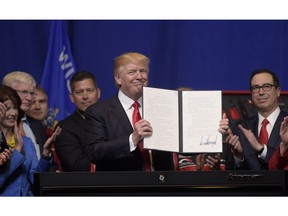 FILE - In this April 18, 2017 file photo, President Donald Trump holds up the "Buy American, Hire American" executive order which he signed during a visit to the headquarters of tool manufacturer Snap-on Inc. in Kenosha, Wis. Immigrants with specialized skills are being denied work visas or seeing applications get caught up in lengthy bureaucratic tangles under federal changes that some consider a contradiction to Trump's promise of a continued pathway to the U.S. for the best and brightest.