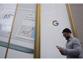 FILE- In this Dec. 17, 2018, file photo a man using a mobile phone walks past Google offices in New York. Alphabet Inc., parent company of Google, reports financial results on Monday, Feb. 4, 2019.