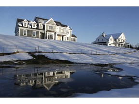 In this Thursday, Feb. 21, 2019 photo a recently constructed home, left, is reflected in water, in Natick, Mass. On Tuesday, Feb. 26, the Commerce Department reports on U.S. home construction in December.
