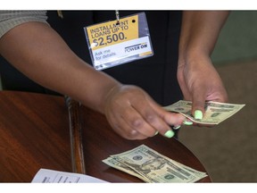 FILE- In this Aug. 9, 2018, photo a manager of a financial services store in Ballwin, Mo., counts cash being paid to a client as part of a loan. The nation's federal financial watchdog has announced its plans to roll back most of its consumer protections governing the payday lending industry. It's the Consumer Financial Protection Bureau's first rollback of regulations under its new Director, Kathy Kraninger, who took over the bureau late last year.