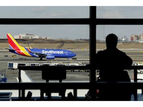 FILE- In this Jan. 25, 2019, file photo a Southwest Airlines jet moves on the runway as a person eats at a terminal restaurant at LaGuardia Airport in New York. Southwest Airlines is lashing out at the union representing its mechanics and suggesting that workers are purposely grounding planes to gain leverage in negotiations over a new contract. Southwest had canceled more than 400 flights, 10 percent of its schedule, by midmorning Wednesday, Feb. 20.