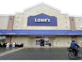 FILE- In this Feb. 23, 2018, file photo a cyclist rides near an entrance to a Lowe's retail home improvement and appliance store in Framingham, Mass. Lowe's Companies, Inc. reports financial results Wednesday, Feb. 27, 2019.