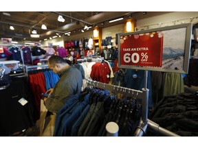 FILE- In this Dec. 24, 2018, photo a last-minute shopper scans his mobile device next to a sign marking discounts on coats at Columbia store as shoppers finish up their Christmas gift lists at the Outlet Malls in Castle Rock in Castle Rock, Colo. The On Thursday, Feb. 14, 2019, the Commerce Department releases U.S. retail sales data for December.