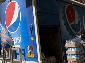 FILE- In this May 7, 2018, file photo a delivery man unloads cases of soft drinks from a Pepsi truck in New York. PepsiCo Inc. reports earns on Friday, Feb. 15, 2019.