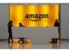 FILE - In this Feb. 14, 2019 file photo, people stand in the lobby for Amazon offices in New York. Amazon is providing a tool that will allow brands to remove listings from its site themselves that they consider to be for counterfeit goods. The online giant is also launching a product serialization service, which allows brands to put unique codes on their products during the manufacturing process. The codes are then scanned by Amazon to confirm authenticity once purchased.