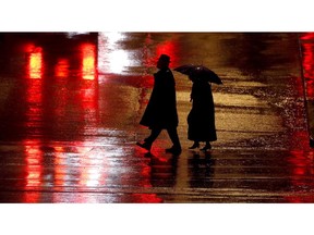 FILE - In this Dec. 26, 2018 file photo, pedestrians are silhouetted against wet pavement as they walk in the Country Club Plaza shopping district in Kansas City, Mo. The number of pedestrians killed on U.S. roads last year was the highest in 28 years, according to a report from a safety organization. Using data reported by states, the Governors Highway Safety Association estimates that 6,227 pedestrians were killed last year. That's up 4 percent from 2017 and 35 percent since 2008.