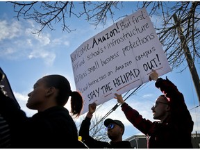 FILE - In this Nov. 14, 2018 file photo, protesters hold up anti-Amazon signs during a coalition rally and news conference opposing Amazon headquarters getting subsidies to locate in the New York neighborhood of Long Island City. Protesters had a long list of grievances to Amazon coming to their community, including the nearly $3 billion in tax incentives that New York was offering them. In its deal with the city, Amazon was promised a spot to build a helipad on or near the new offices. Some people questioned the optics of high-flying executives buzzing by a nearby low-income housing project.