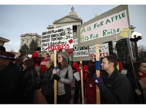 FILE - In this Wednesday, Jan. 30, 2019, file photo, teachers from the Denver Public Schools carry placards as they wait to march after a rally in support of a strike outside the State Capitol in Denver. Denver teachers are planning to strike Monday, Feb. 11, 2019 after failed negotiations with the school district over base pay.