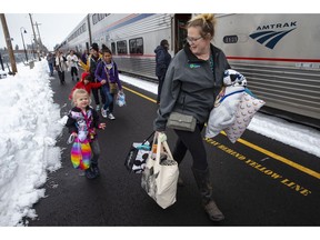 Jordyn Hooper, right, and her four-year-old daughter Quinn Hooper, left, join other passengers as they disembark from an Amtrak train in Eugene, Ore, Tuesday, Feb. 26, 2019 after being stranded overnight in the mountains east of town.