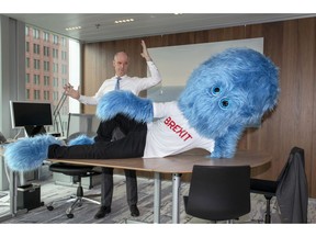 This image made available by the Netherlands Foreign Ministry on Thursday Feb. 14, 2019, shows Foreign Minister Stef Blok and a hairy blue Brexit monster on a desk in The Hague, Netherlands. The Dutch government has enlisted a new ally in its battle to prepare businesses for the impending departure of Britain from the European Union, a hairy blue Brexit monster.  A tweet posted Thursday on Foreign Minister Stef Blok's official Twitter feed shows the monster, wearing a white T-shirt emblazoned with the word Brexit in red capital letters, lying across a desk.