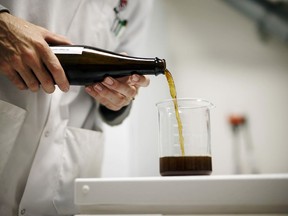 A lab technician pours a bottle of beer brewed using cannabis at the Province Brands of Canada laboratory in Belleville, Ont.