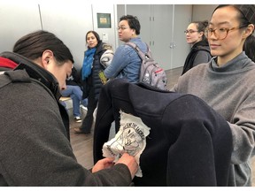 Jeff Chen, left, affixes a "Defend the Sacred" logo to Su Chon's jacket ahead of a Bureau of Land Management hearing Monday, Feb. 11, 2019, in Anchorage, Alaska. The two Anchorage residents planned to oppose drilling as the federal agency accepted public comments on a draft environmental review on drilling within the coastal plain of the Arctic National Wildlife Refuge.
