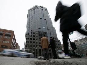 Pedestrians wait to cross the street in front of the SNC-Lavalin Group Inc., headquarters in Montreal.