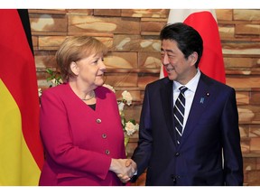 German Chancellor Angela Merkel, left, shakes hands with Japanese Prime Minister Shinzo Abe prior to their meeting at Abe's official residence in Tokyo, Monday, Feb. 4, 2019.