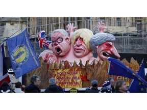 Anti-Brexit demonstrators stand next to a van with large cartoon style portraits of leading British politicians including, from right, Prime Minister Theresa May, Boris Johnson, Michael Gove, David Davis, outside the Palace of Westminster in London, Thursday, Feb. 14, 2019. British lawmakers are holding another series of votes on Brexit legislation Thursday.