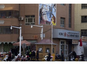 FILE - In this Nov. 5, 2017, file photo, residents pass by a security checkpoint and surveillance cameras mounted on a street in Kashgar in western China's Xinjiang region. The Chinese database Victor Gevers found online was not just a collection of old personal details. The discovery by Gevers, a Dutch cybersecurity researcher who revealed it on Twitter last week, has given a rare glimpse into China's extensive surveillance of Xinjiang, a remote region home to an ethnic minority population that is largely Muslim. The area has been blanketed with police checkpoints and security cameras that apparently are doing more than just recording what happens. The database Gevers found appears to have been recording people's movements tracked by facial recognition technology, he said, logging more than 6.7 million coordinates in a span of 24 hours.