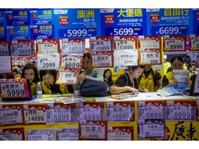 In this March 3, 2018, photo, people check on travel packages offered by travel agencies during the Guangzhou International Travel Fair in Guangzhou in south China's Guangdong province. Travelers in China were blocked from buying plane tickets 17.5 million times last year as a penalty for failing to pay fines or other offenses. The Chinese government reported this week on penalties imposed under a controversial "social credit" system the ruling Communist Party says will improve public behavior. (Chinatopix via AP)